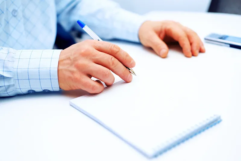 rs=w_800,cg_true A person writing on paper with a pen.