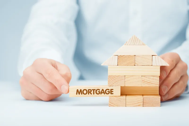 rs=w_800,cg_true,m (1) A person is building a house with the word mortgage on it.